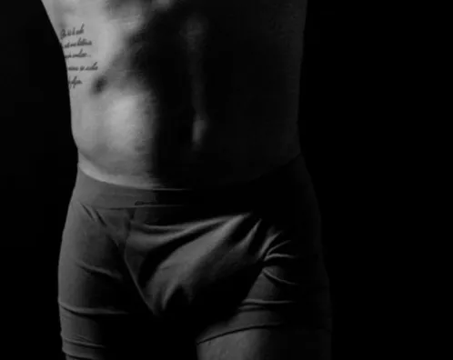 Homem de cueca em foto preto e branco, em fundo escuro
